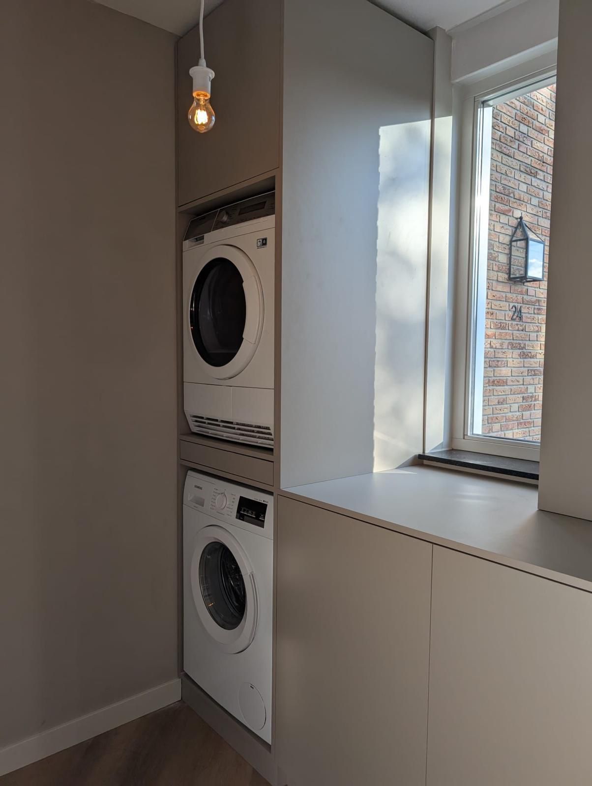Wasruimte met gestapelde wasmachine en droger